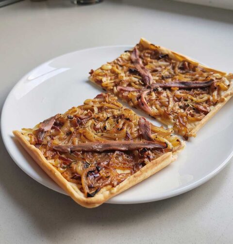 2 stukken Franse uienpizza op een bord.