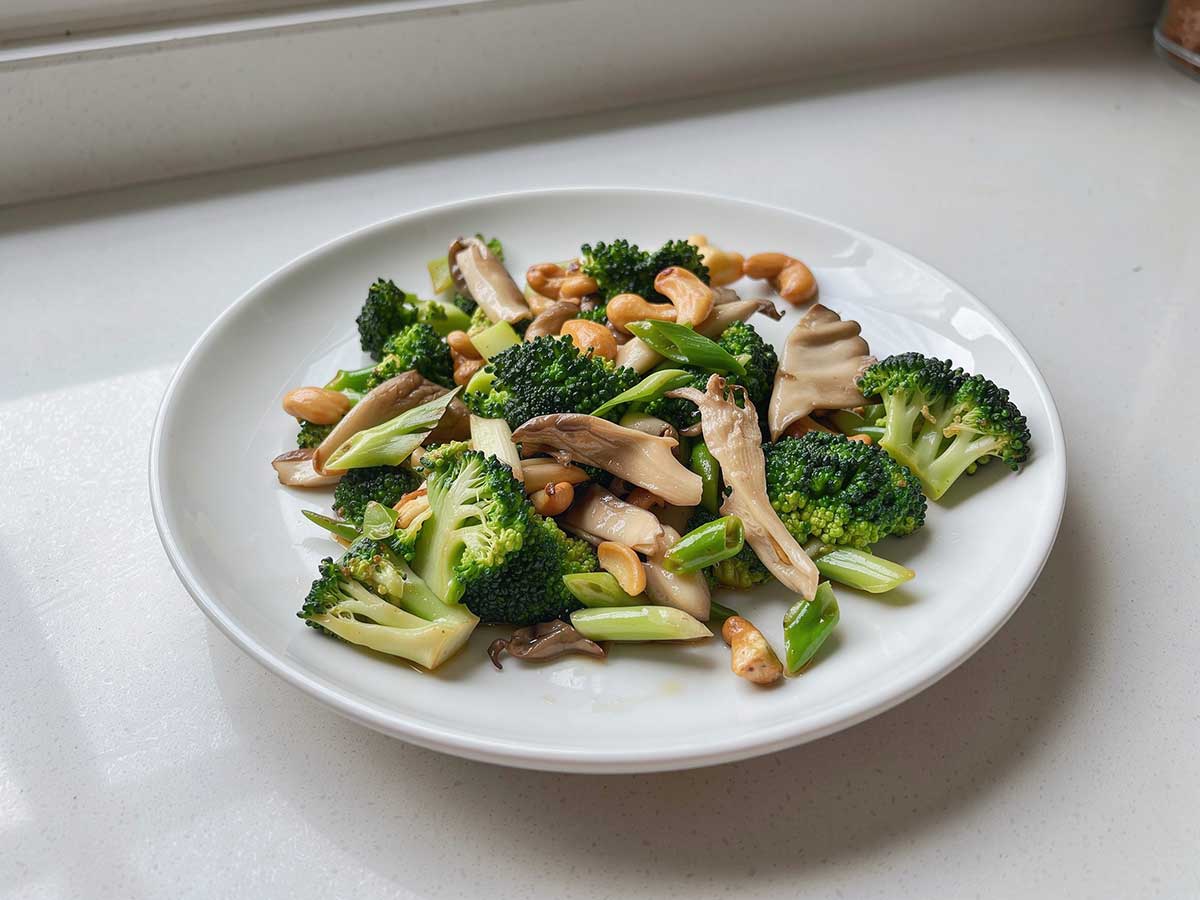 Een bord met geroerbakte broccoli en stukken oesterzwam.
