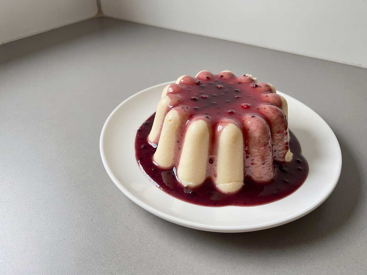Een hele griesmeelpudding op een bord met bessensap.