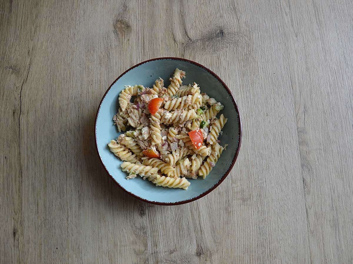 Koudepastasalade met tonijn in een lichtblauw schaaltje.