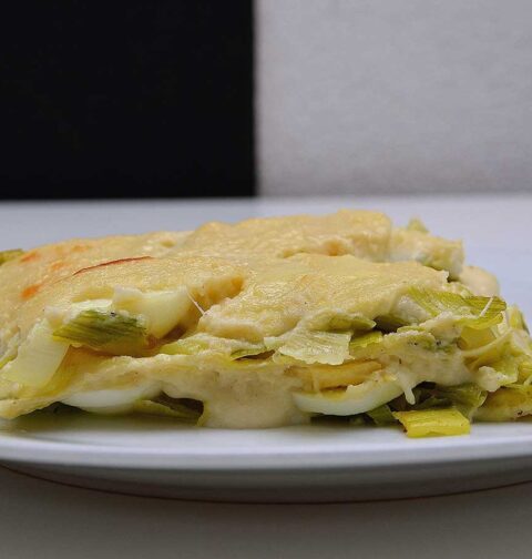 Lasagne met prei, maar zonder vlees op een wit bord.