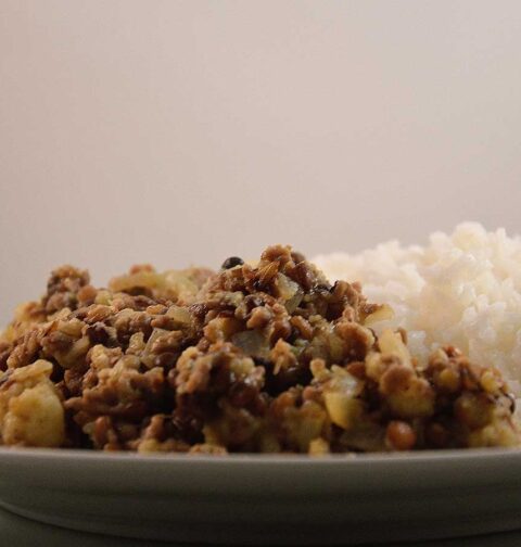 Linzen-bloemkoolcurry met rijst, op een wit bord.